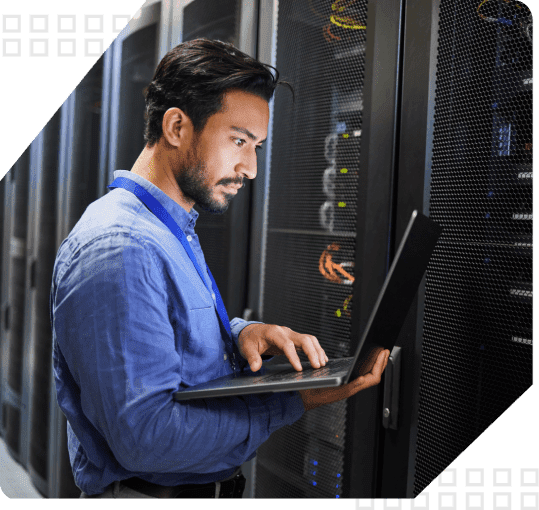 Man working on laptop in server room.